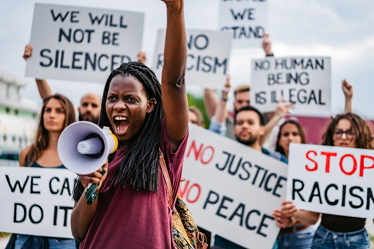 Woman speaking in megaphone in front of crowd.