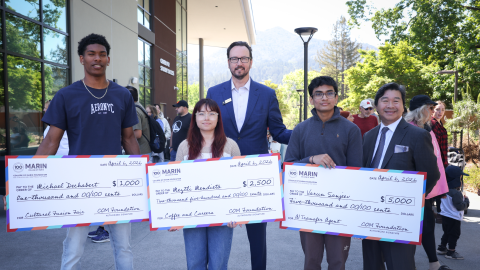Image of Ideation Challenge winners holding big checks and standing with President Jonathan Eldridge and faculty member Tim Wat